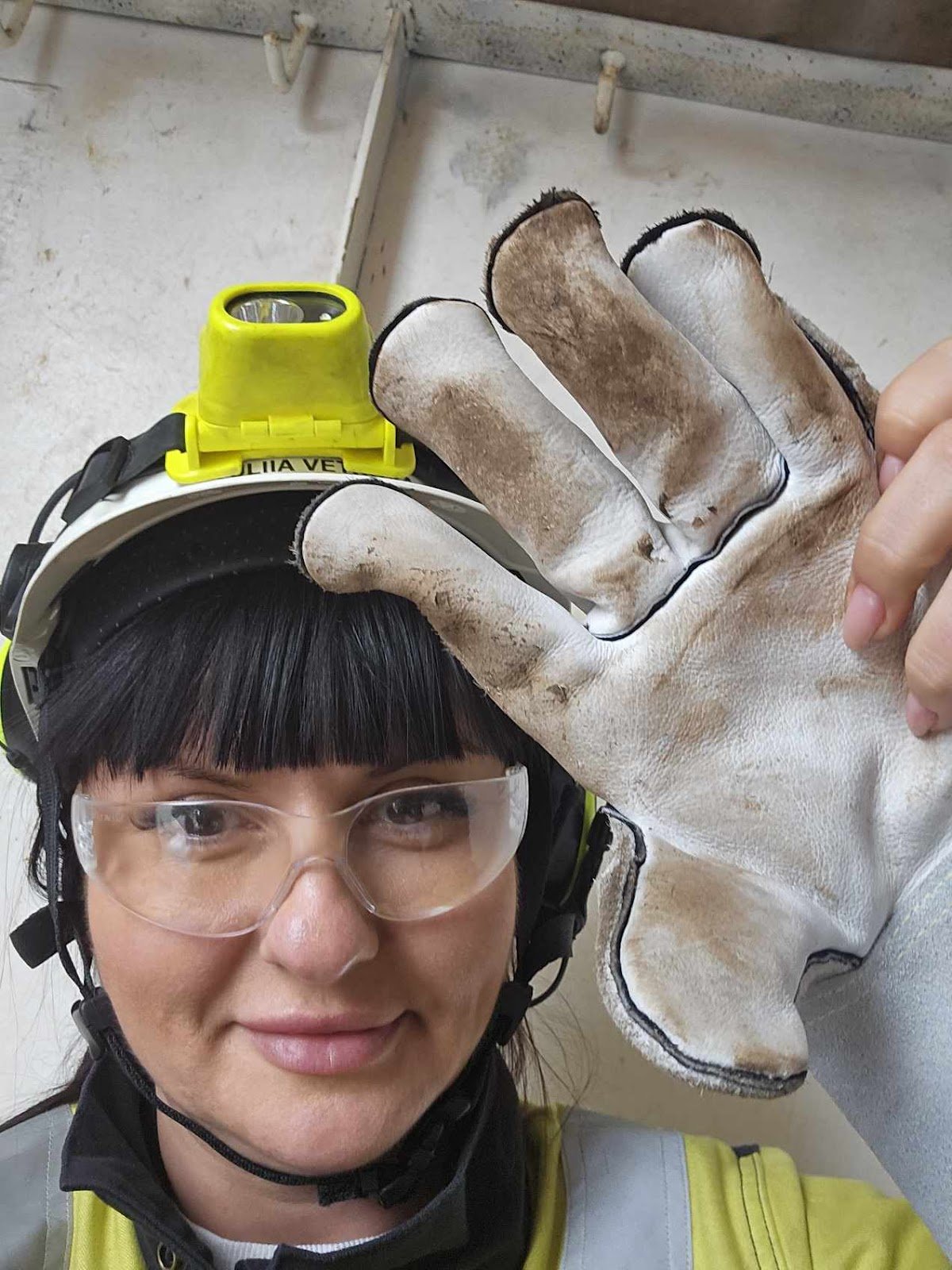 Юлія, вдягнута в форму, каску, захисні окуляри, показує робочі рукавички, які обов’язково треба носити. Фото з особистого архіву