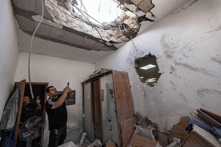 Люди фотографують зруйновану синагогу після потрапляння в неї ракети, випущеної з Сектору Гази, Ашкелон, Ізраїль, 16 травня 2021 року. Фото: AP/Tsafrir Abayov