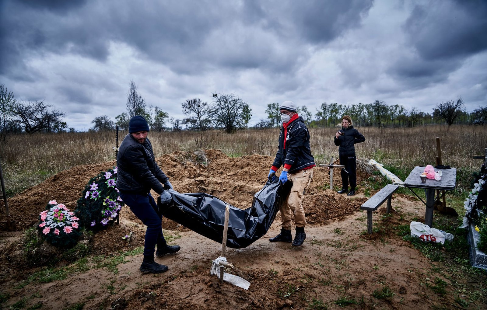 The volunteers of Cargo 200 mission are carrying a body from the grave to the vehicle to take it to the morgue