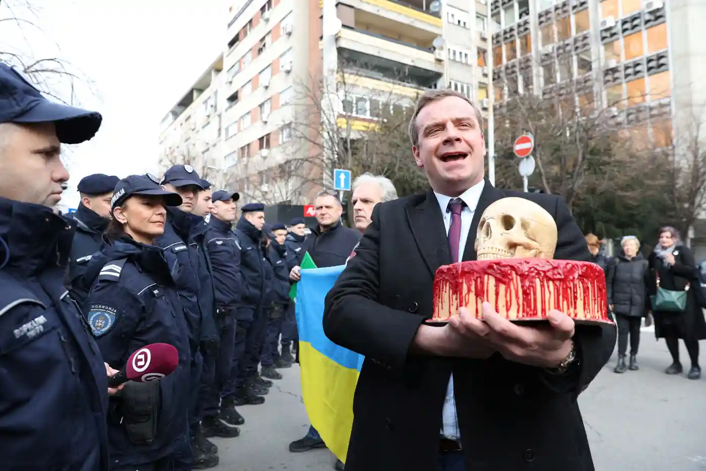 Сербський активіст Седомир Стойкович передає закривавлений торт і череп поліцейським, які охороняють посольство Росії в Белграді. Фото: Zorana Jevtic/Reuters
