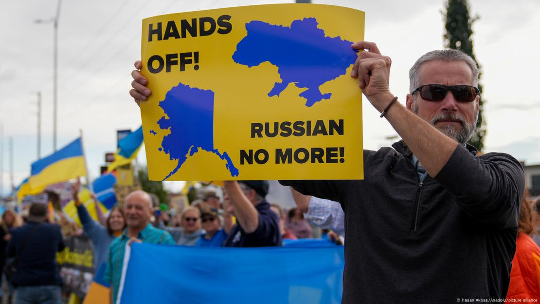 Плакат на демонстрації із контурами мап Аляски та України. Фото: Hasan Akbas/Anadolu/picture alliance