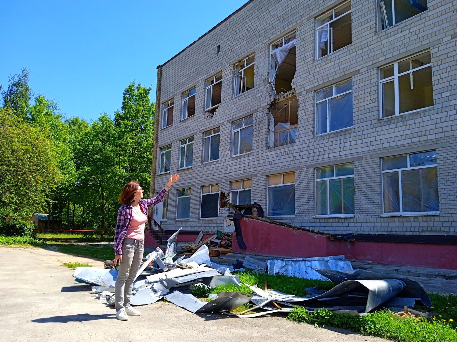 Ганна Гнатюк вказує на будівлю сільської школи, яку зруйнували російські військові