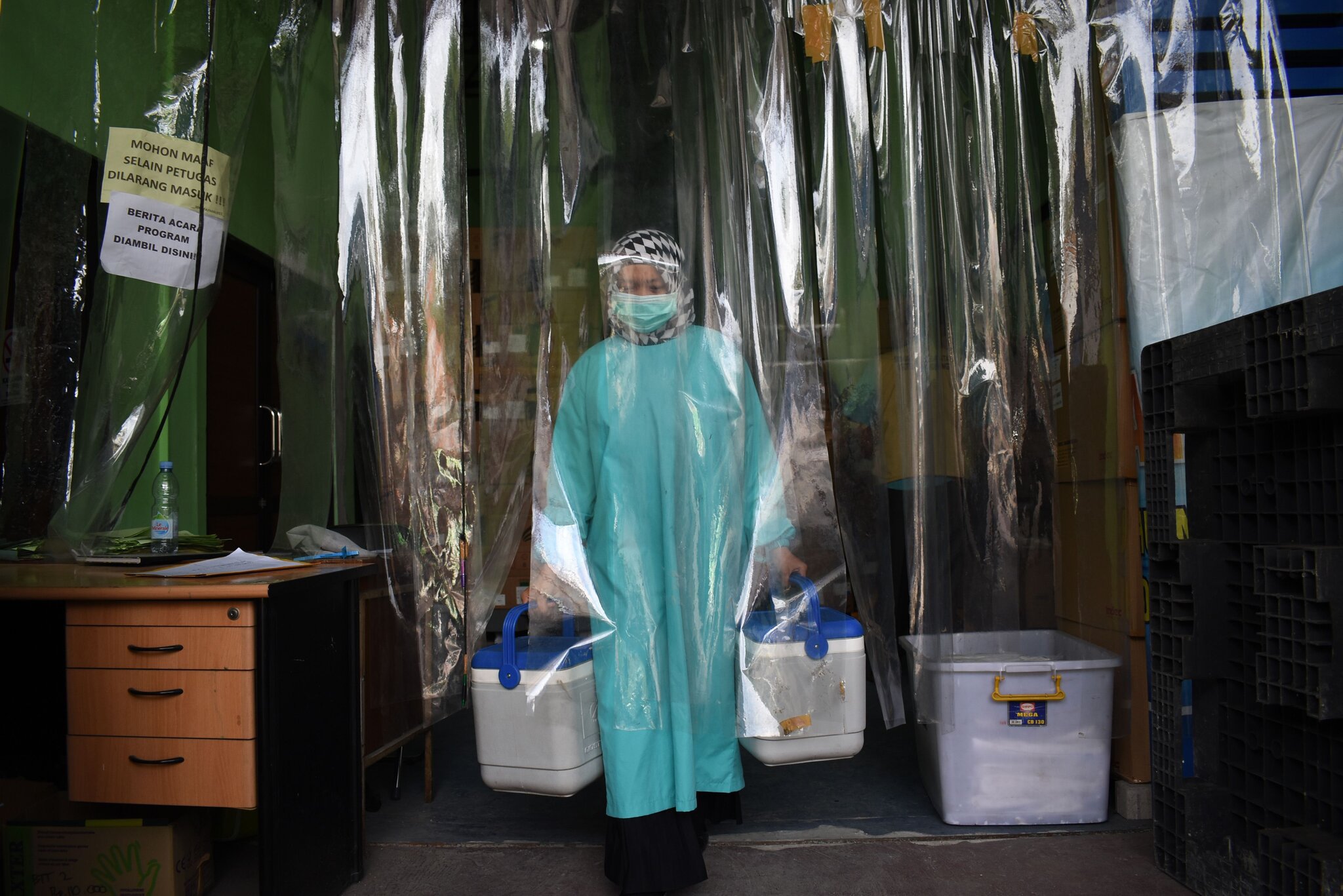 Індонезійський медик із контейнерами несе вакцину Sinovac, фото Timur Matahari/Agence France-Presse